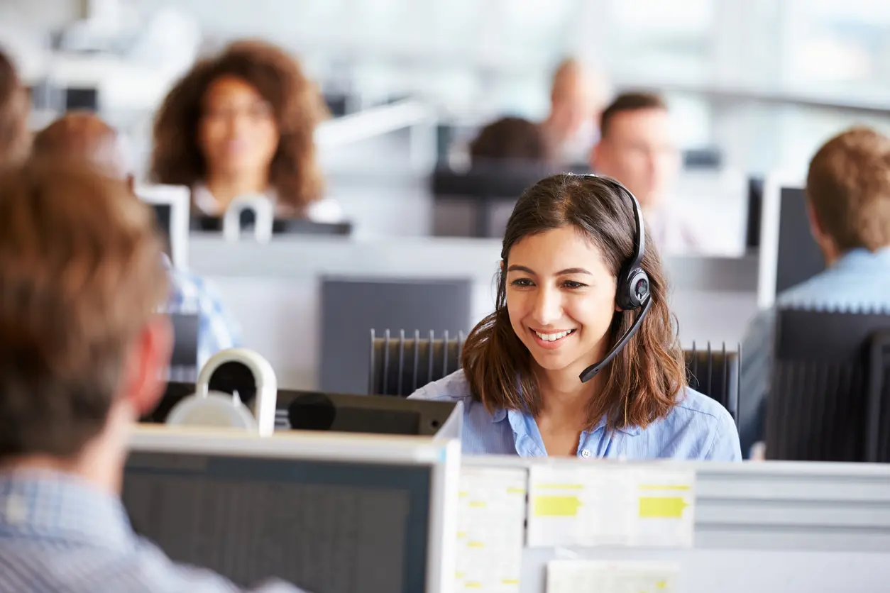 Young woman working in call centre, surrounded by colleagues woman using computer